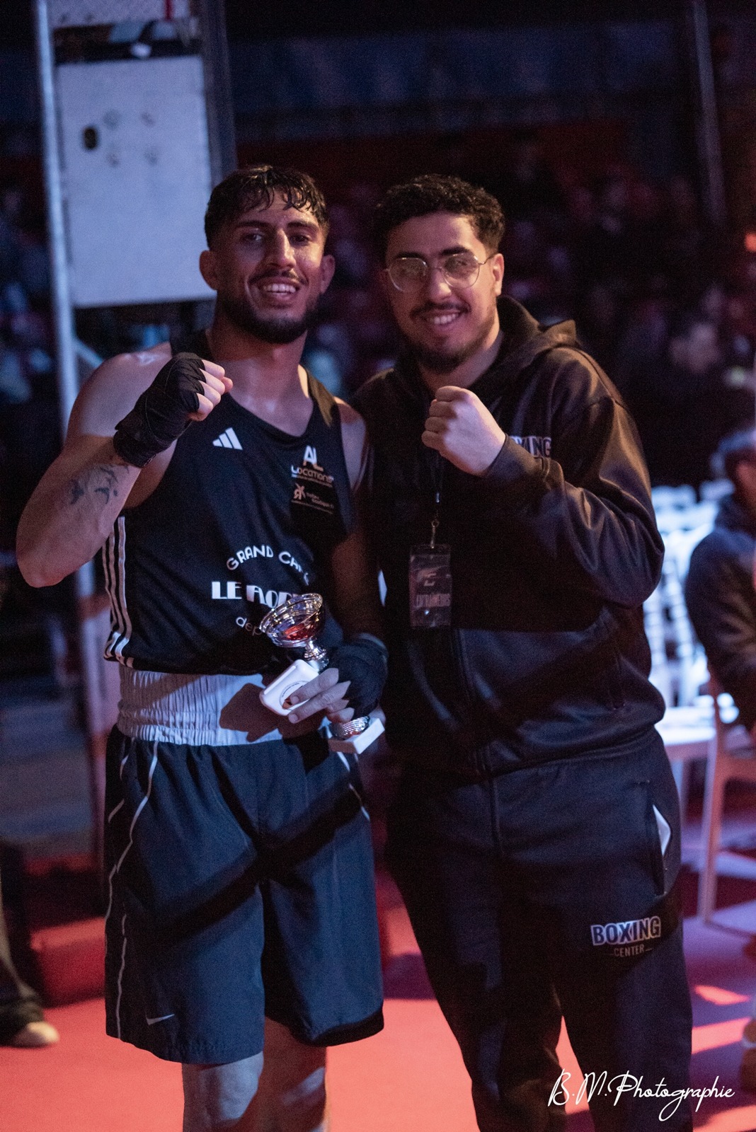 Mehdi, coach de boxe anglaise à Toulouse, aux côtés d’un boxeur et de son trophée